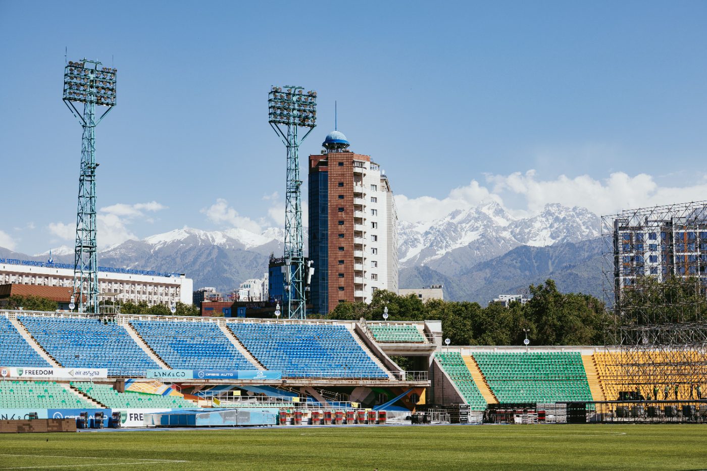 A striking view of a stadium in Almaty with snow-capped mountains in the background.