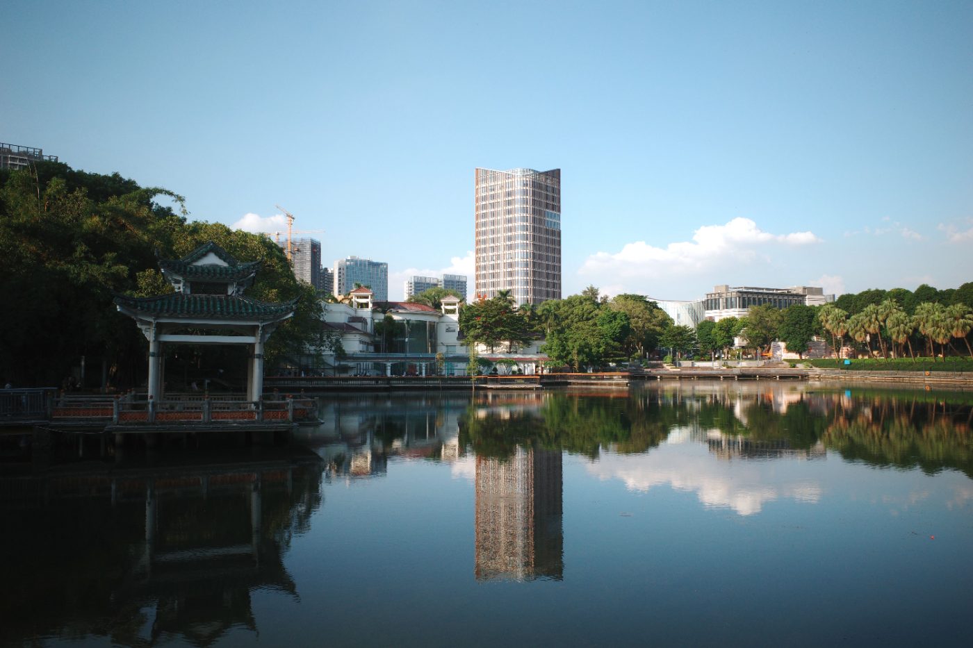 Scenic view of Foshan's urban skyline reflecting on a lake under a clear sky.