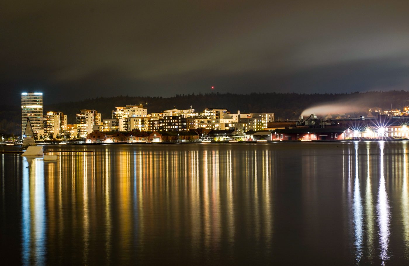 Illuminated urban skyline reflecting on the water in Jönköping at night.