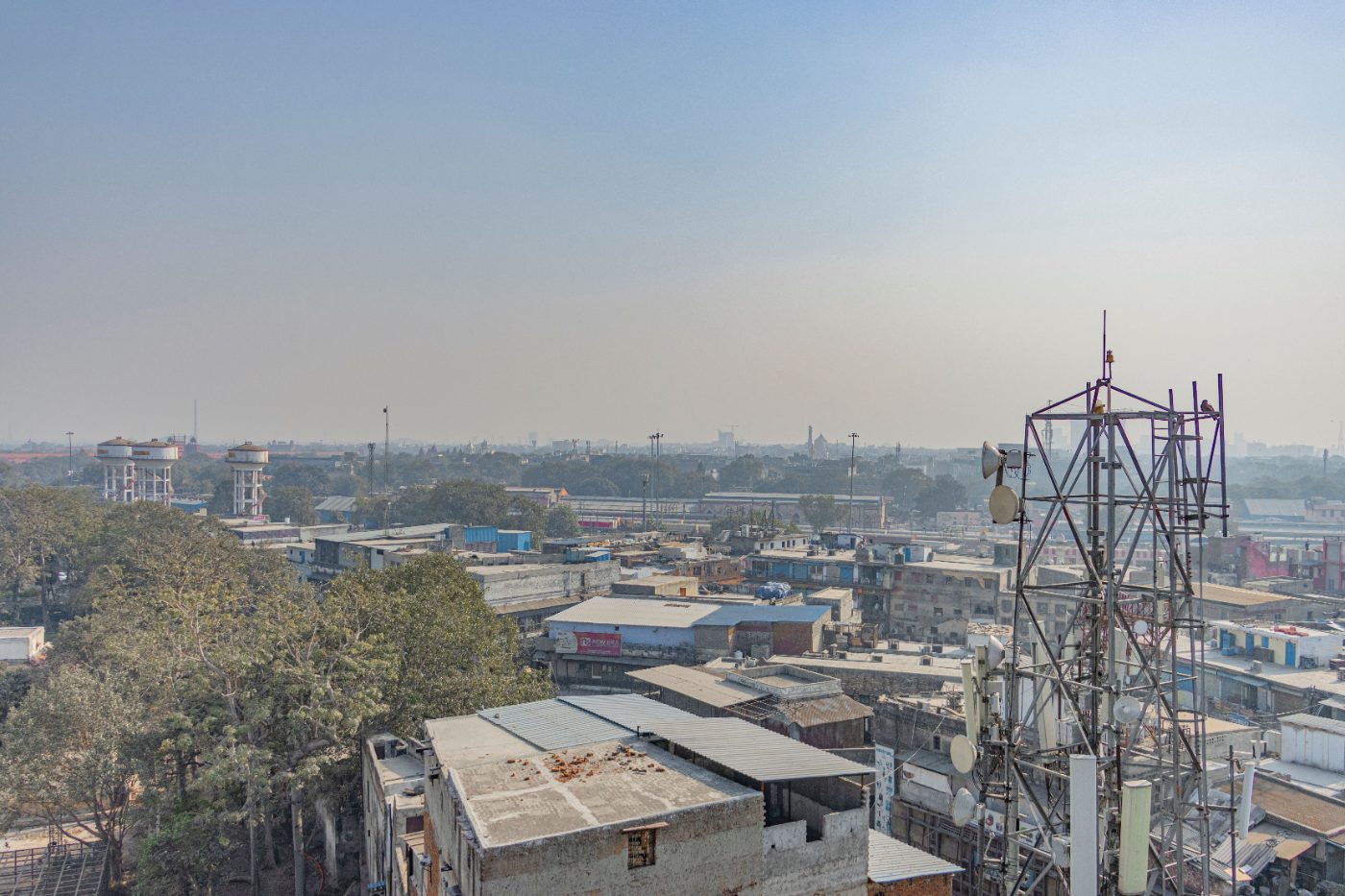 Aerial view of urban buildings and trees with a telecom tower in New Delhi, India.
