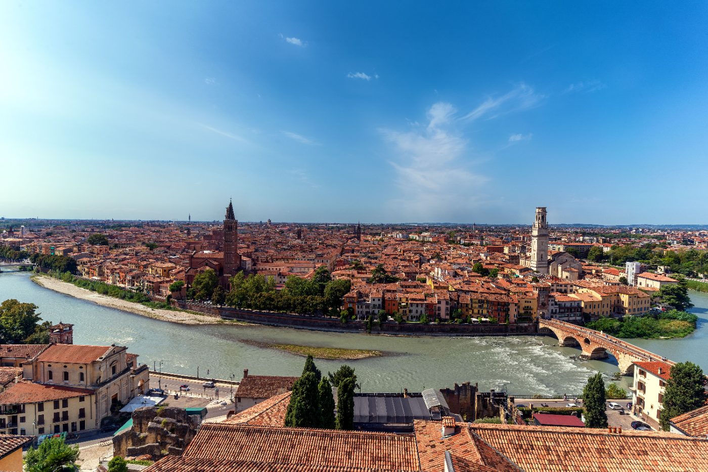 Stunning aerial view of Verona cityscape, featuring the Adige River winding through historic architecture under a clear blue sky.